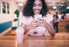 A woman looks at a mobile phone, smiling